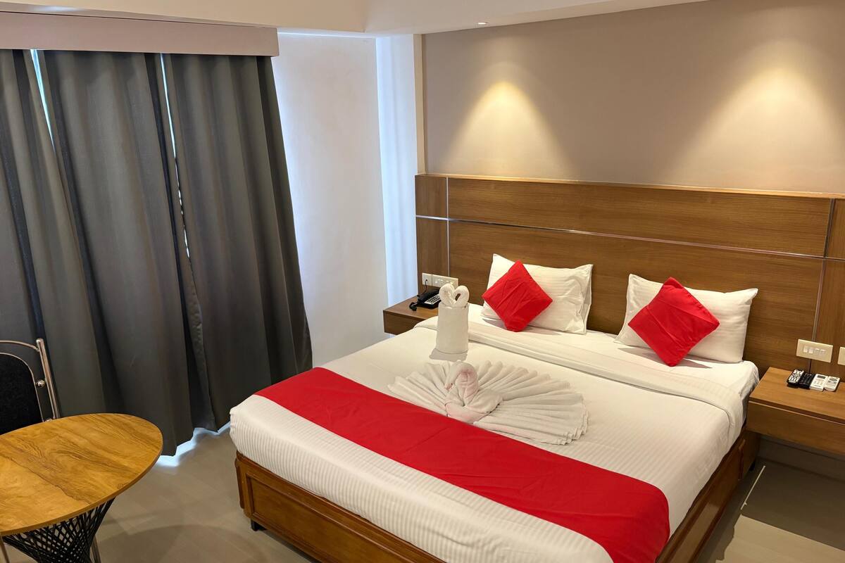 Una habitación de hotel con una cama, una mesita de noche de madera, una mesa y una silla.
