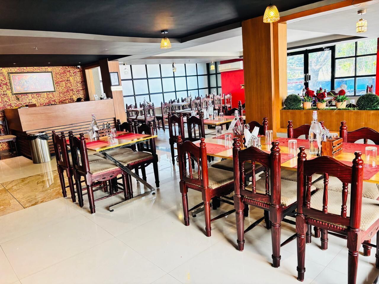 A restaurant with wooden chairs and tables, a bar area, and large windows.