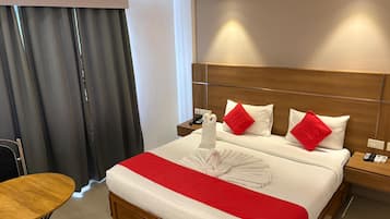 Una habitación de hotel con una cama, una mesita de noche de madera, una mesa y una silla.
