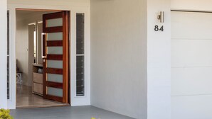 A modern entrance with a wooden door and a garage door marked with the number 84. - “Sunrise & Sunset” – Panoramic Ocean Views (Copacabana)