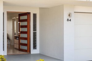 A modern entrance with a wooden door and a garage door marked with the number 84. - “Sunrise & Sunset” – Panoramic Ocean Views (Copacabana)