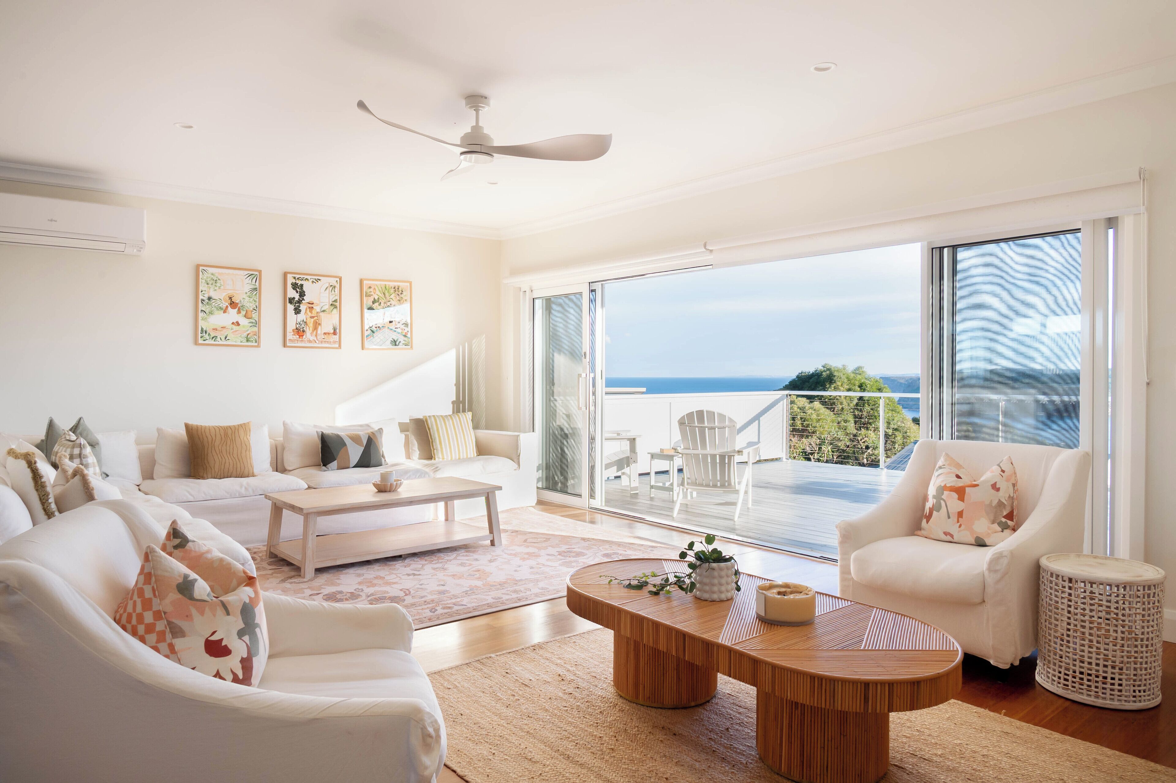 A spacious living room with a large sliding glass door leading to a balcony with a view of the sea.