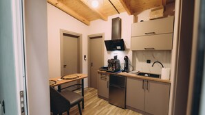 Cocina compacta con armarios de madera, horno integrado y cafetera.