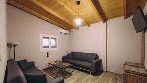 Un salón moderno con techo de madera, un sofá gris, una mesa de centro y un televisor de pantalla plana montado en la pared.
