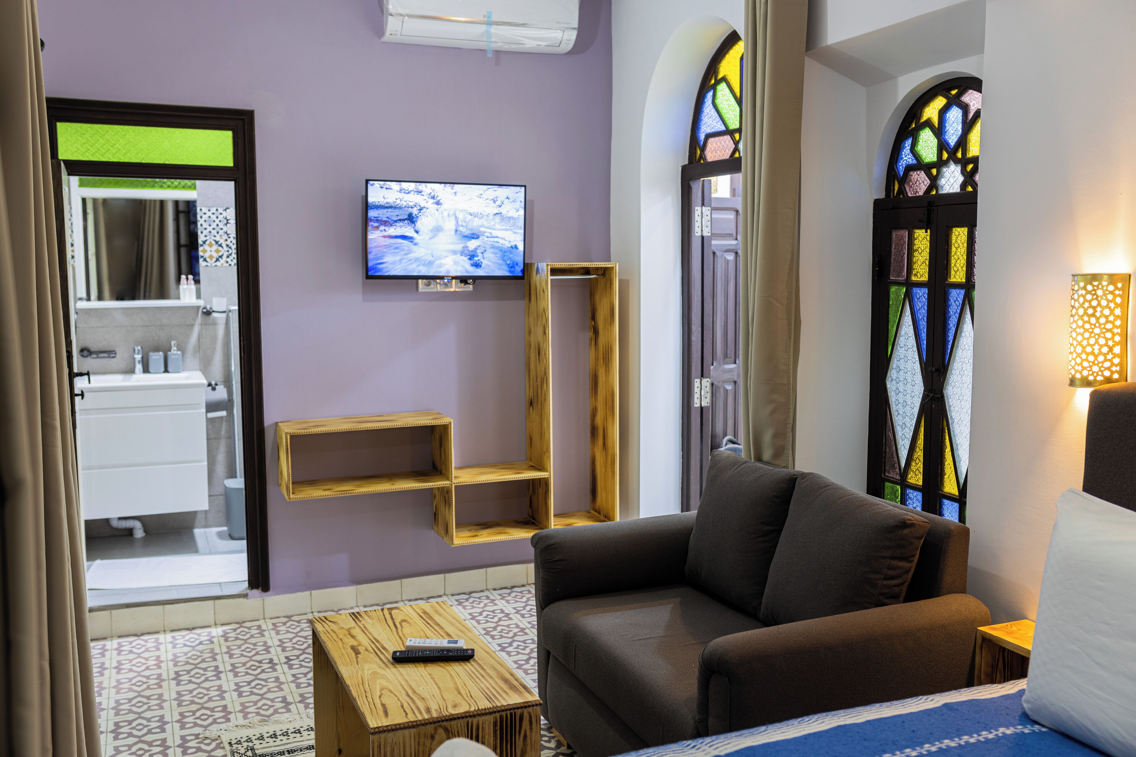 Un salon moderne avec un canapé, un téléviseur fixé au mur et une étagère en bois.