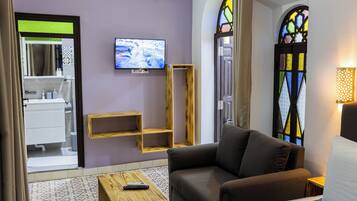 Un salon moderne avec un canapé, un téléviseur fixé au mur et une étagère en bois.