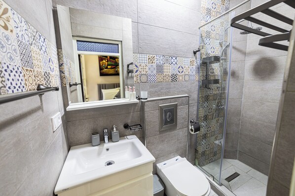 Egy modern fürőszoba mosdókagylóval, WC-vel és zuhanyzóval.