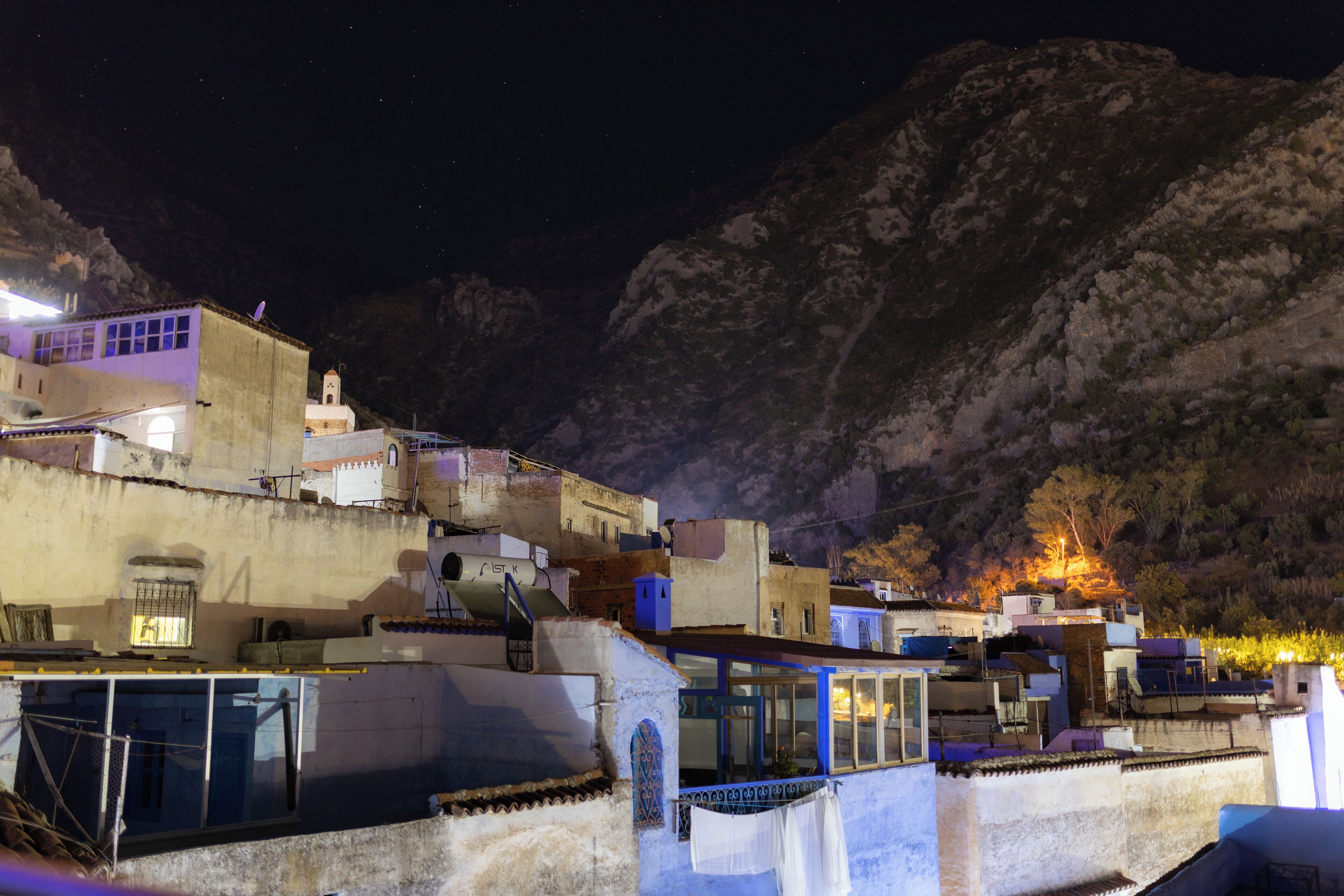 A hillside village with buildings featuring traditional architecture, including flat roofs and terracotta tiles.