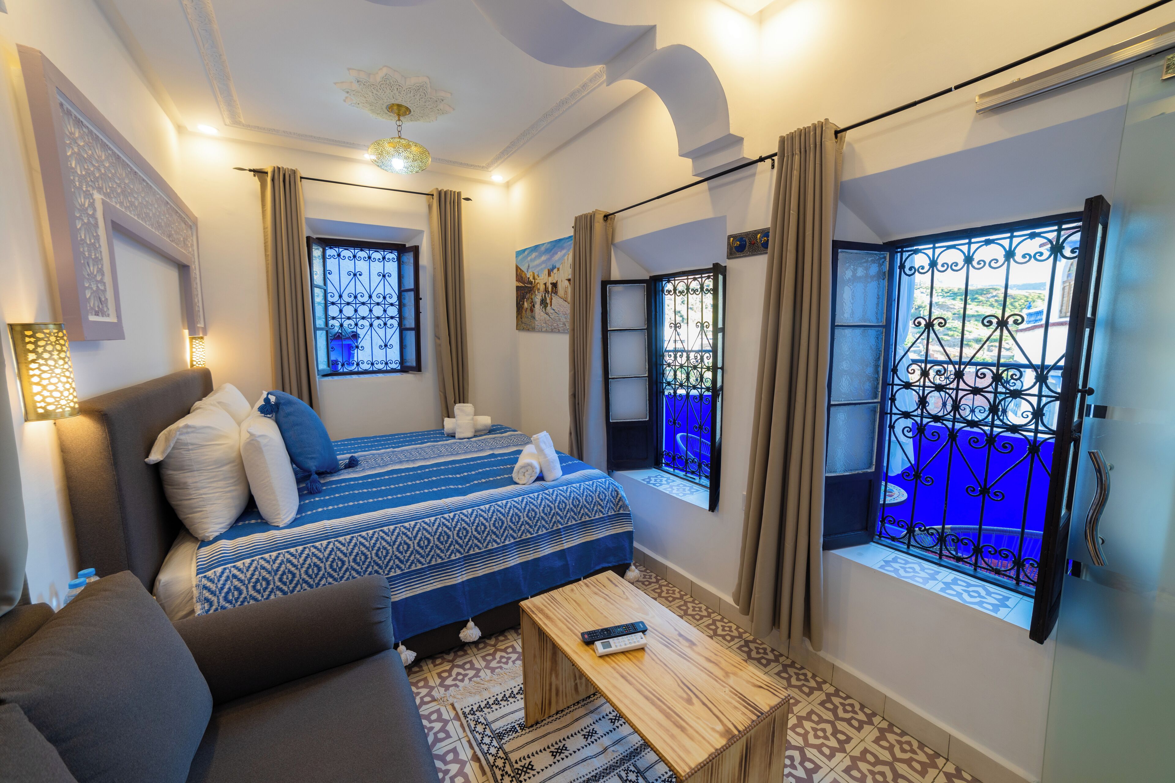 Habitación de hotel con cama, sofá, una mesita y ventana con vistas.