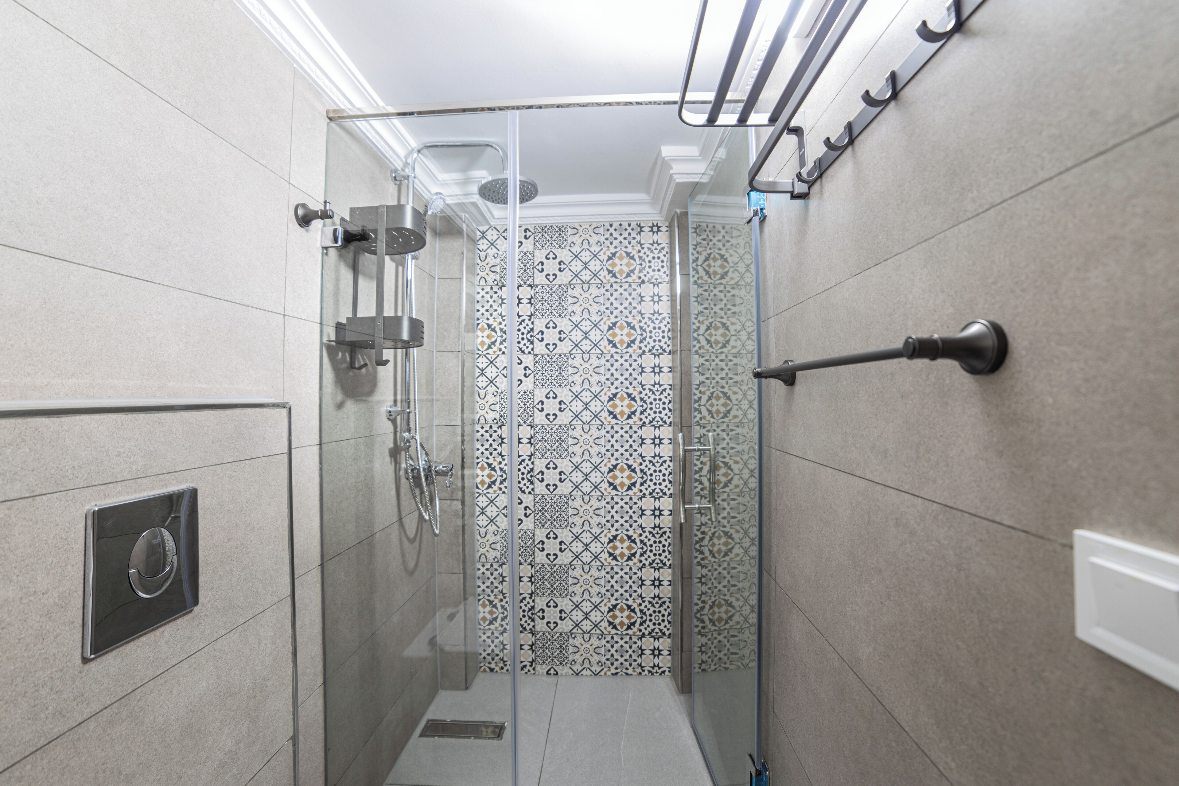 A modern bathroom with a glass-enclosed shower, patterned tiles, and a towel rack.