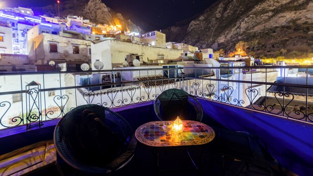 Ein Balkon mit Tisch, Stühlen und einer Kerze.