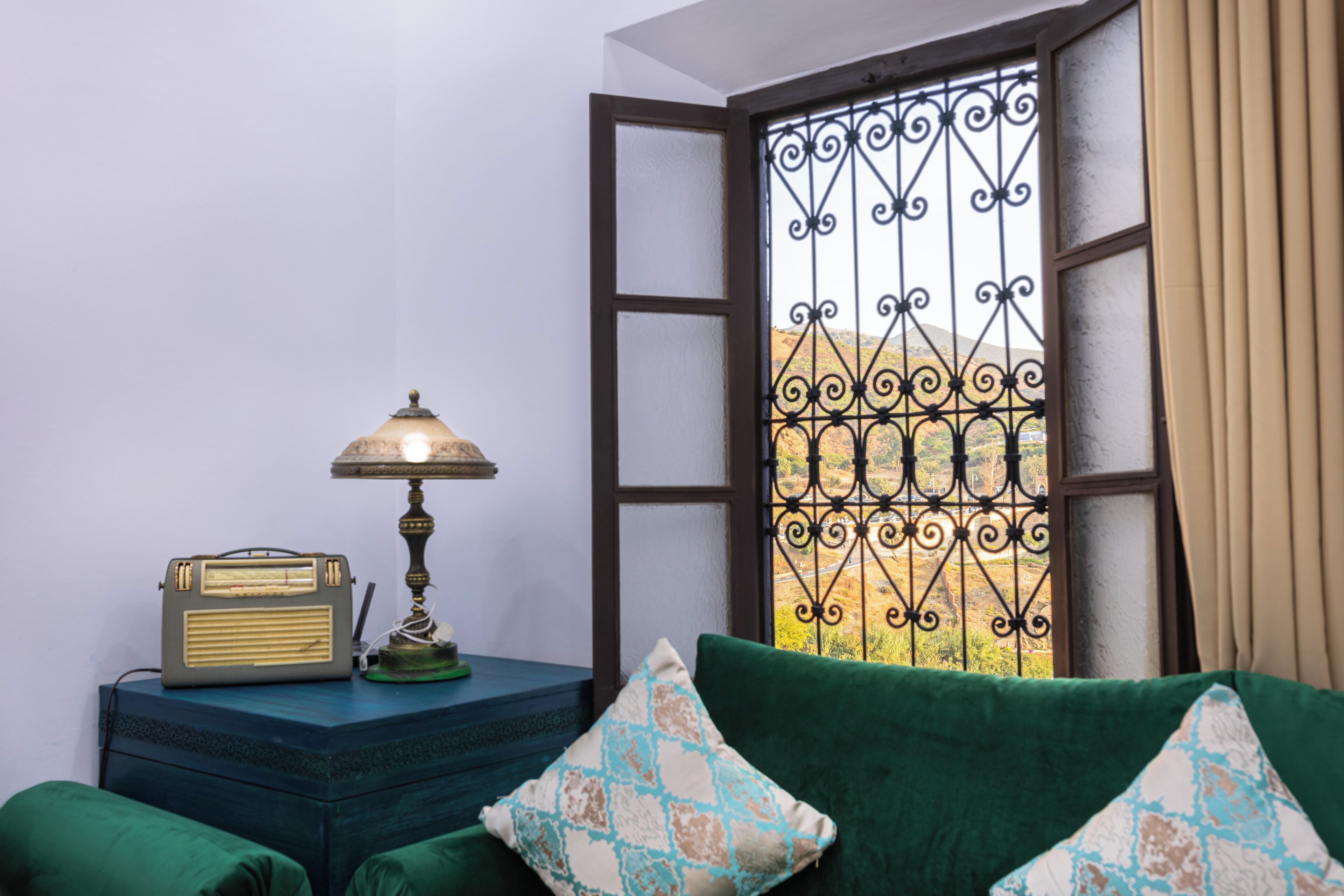 Una habitación con un sofá verde, una radio antigua y una lámpara de mesa.
