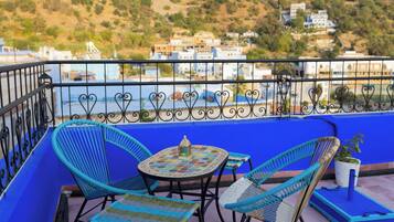 A balcony with blue walls, a small table with a decorative lantern, and wicker chairs.
