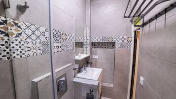 Een moderne badkamer met patroon betegelde vloeren, een glazen douchecabine, een wastafel en een toilet.