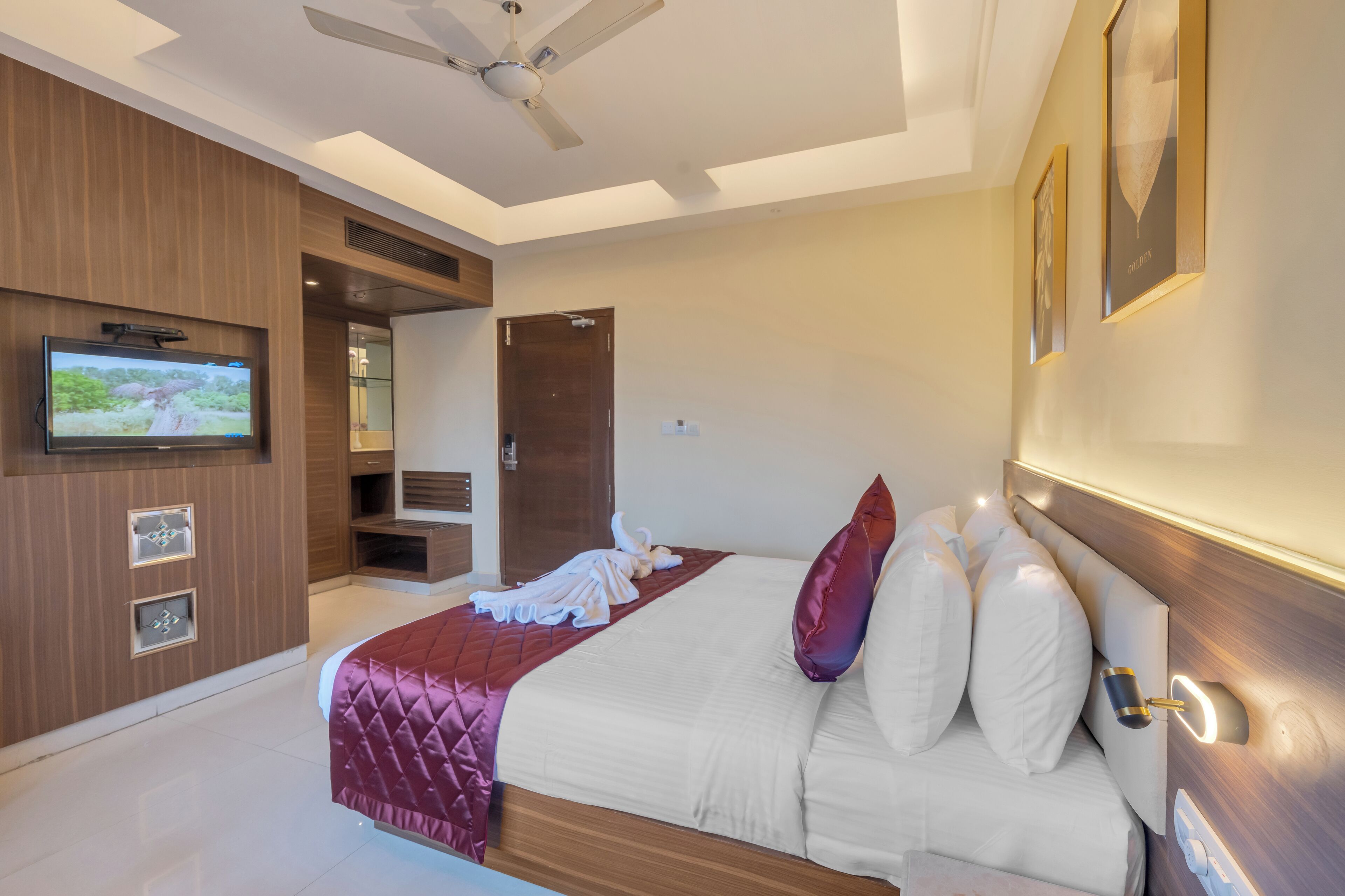 Une chambre d’hôtel moderne dotée d’un grand lit, d’un téléviseur à écran plat fixé au mur et d’un ventilateur de plafond.