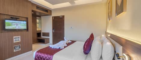 A modern hotel room with a large bed, a flat-screen TV mounted on the wall, and a ceiling fan.