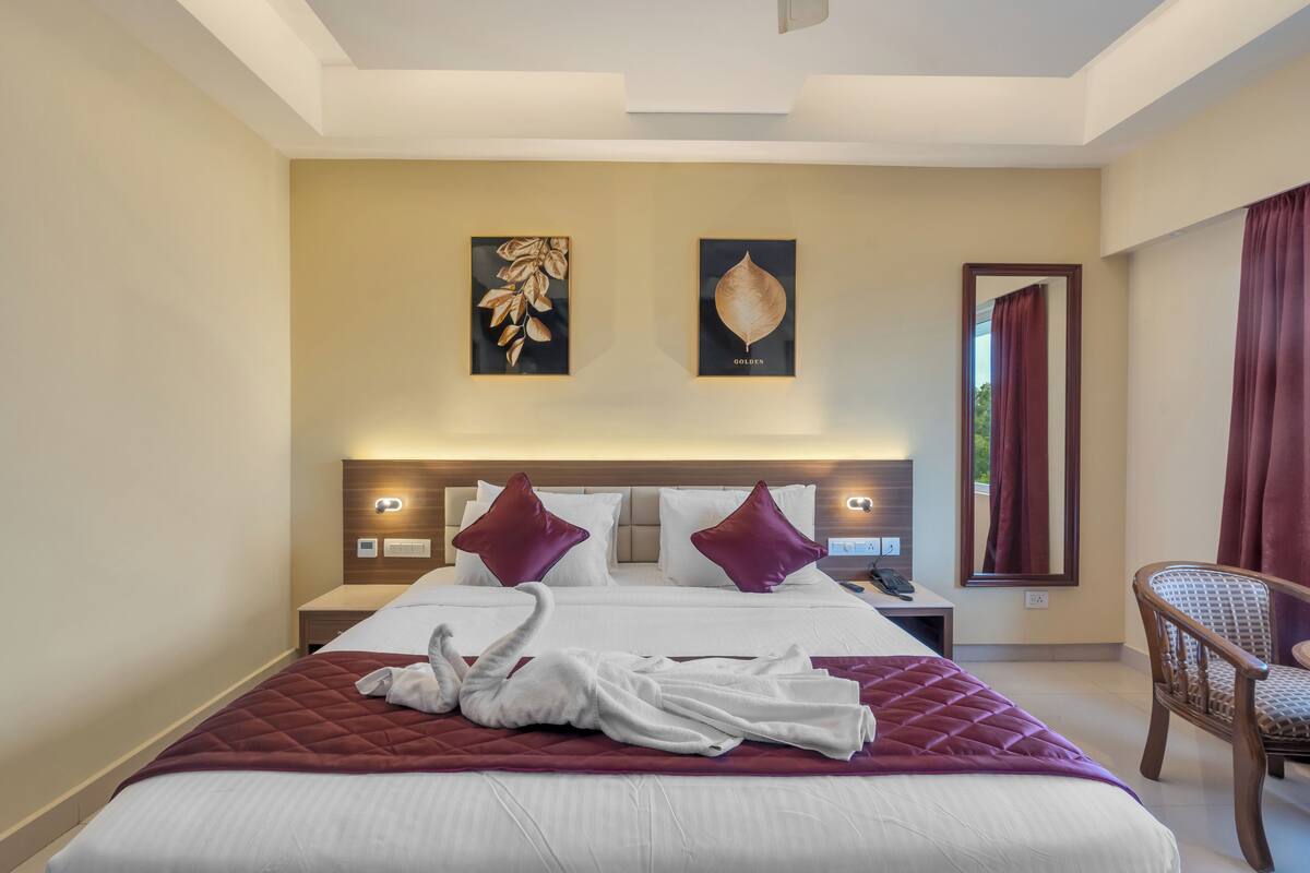 Een hotelkamer met een groot bed, twee wandlampen, een spiegel en een stoel.