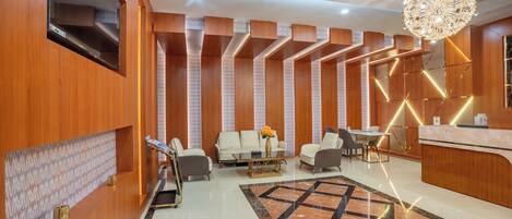 A modern lobby with a reception desk, seating area, and a decorative chandelier.