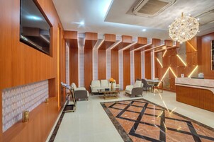 Un vestíbulo moderno con mostrador de recepción, zona de estar y una lámpara decorativa.