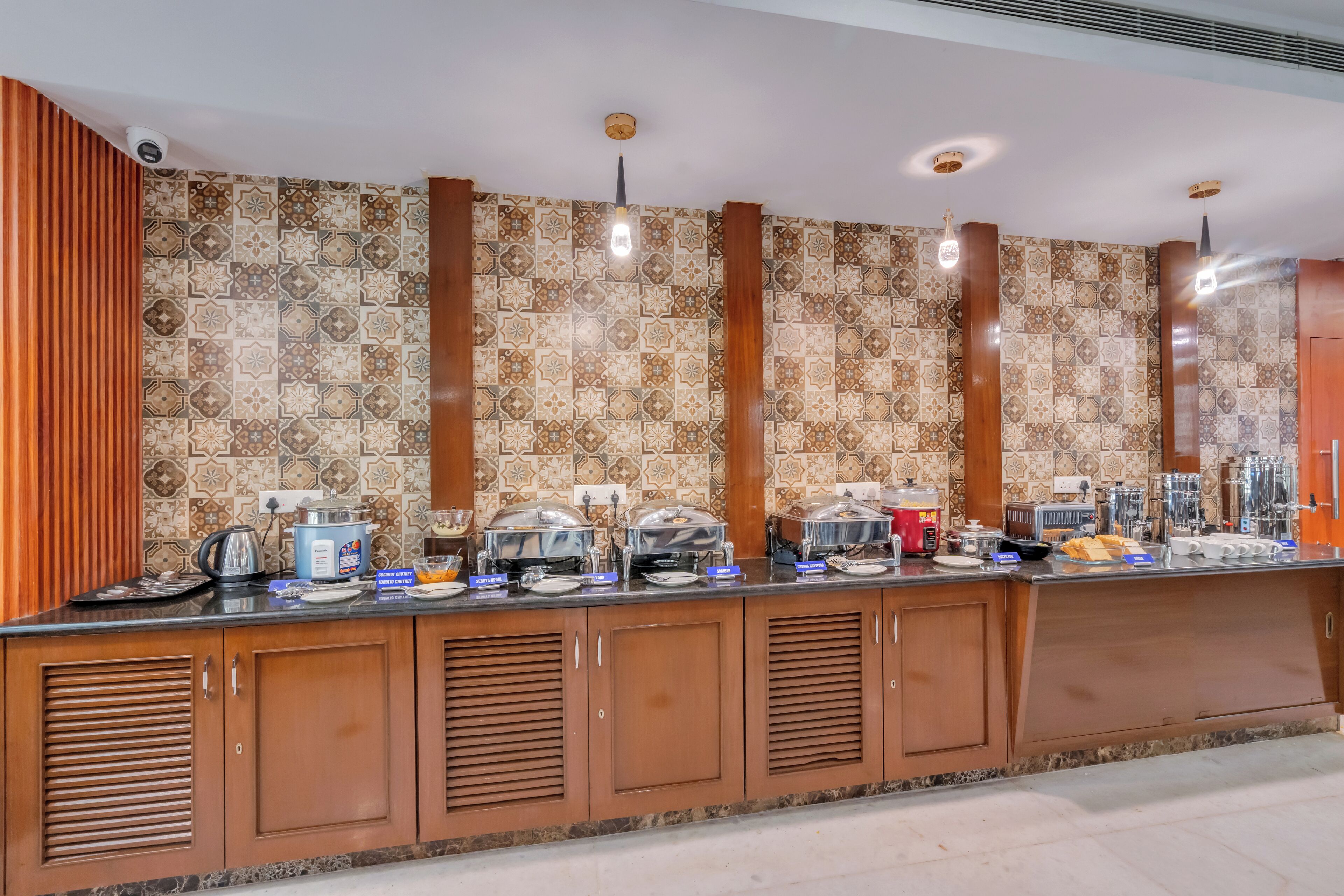 Un comptoir de buffet agrémenté d’un mur recouvert de carreaux décoratifs, de meubles en bois et de divers plats.
