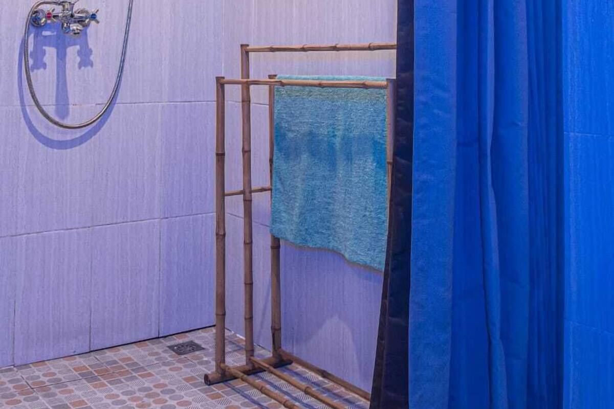 A bathroom with a shower, a towel rack, and a blue curtain.
