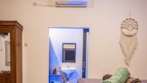 Ein Schlafzimmer mit einem hölzernen Bett, einem Nachttisch, einem Spiegel und einer Wand-Klimaanlage.