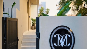 A modern building entrance with a black gate, a staircase, and a logo on the wall. - Monarco Executive Rooms (Rhodes)