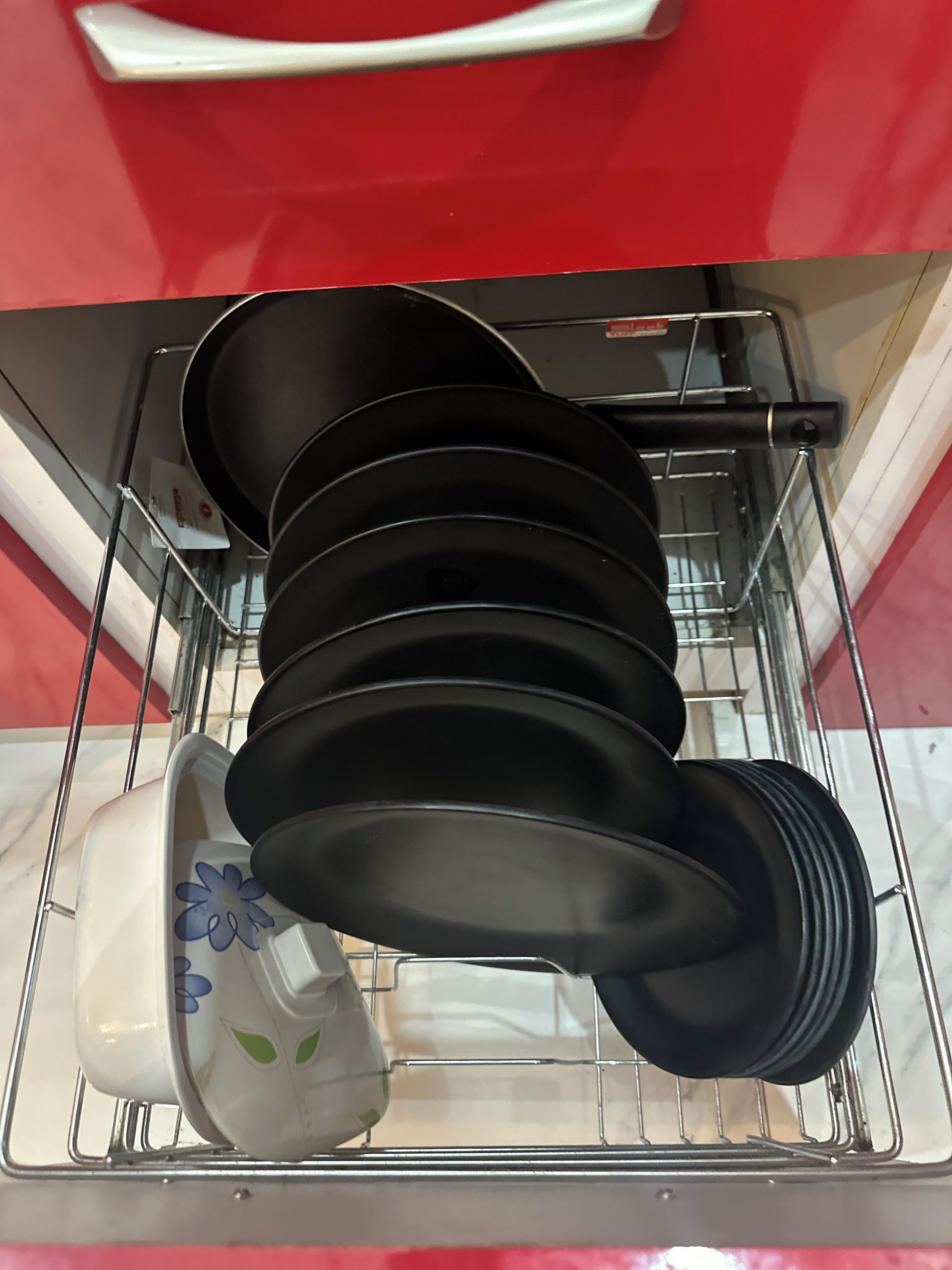 A kitchen with a dish rack holding several black plates and a white mug with a floral design.