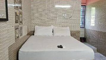 Un dormitorio con cama, ventilador de techo, aire acondicionado y ventana.