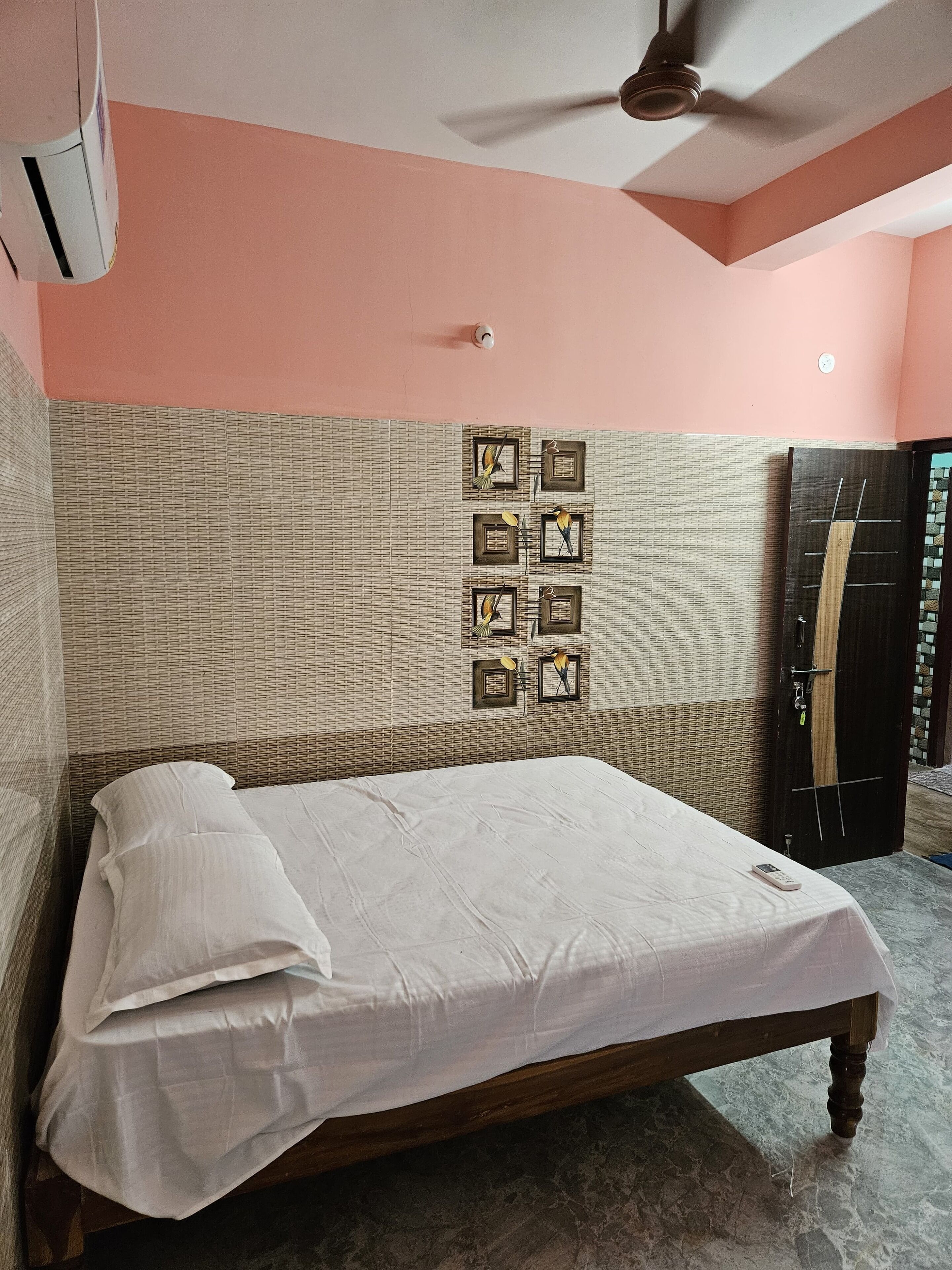 Cama bem arrumada em quarto com parede texturizada e ventilador de teto.