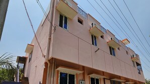 A two-story building with a flat roof, multiple windows, and a staircase leading to the entrance. - Swathi Rooms  (Tiruvannamalai)