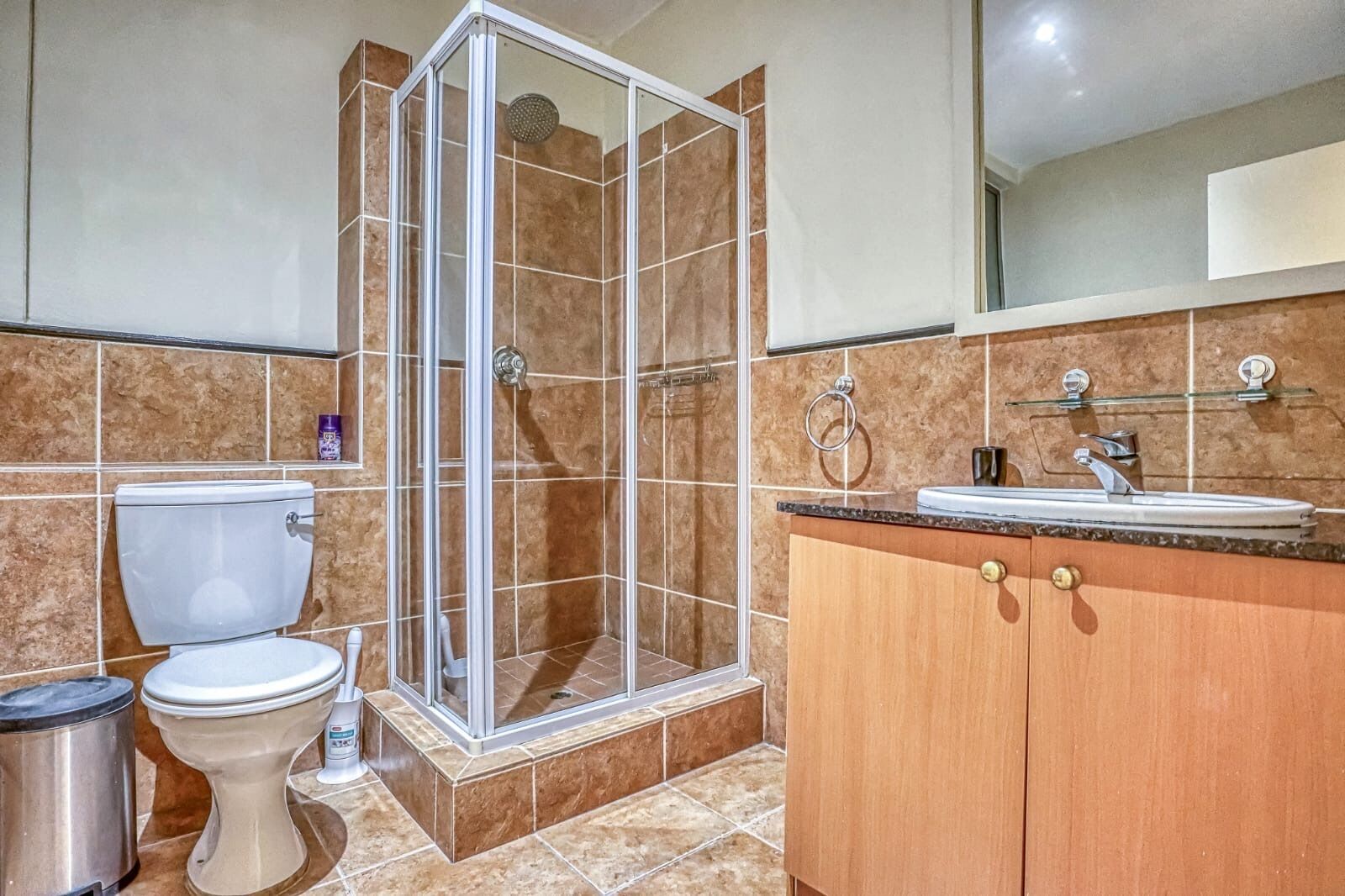 A bathroom with a shower, toilet, sink, and cabinet.
