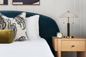 A bedroom with a bed, pillows, a bedside table with a lamp, and a clock. - MidMod Bungalow 5BR Heated Pool (Austin)