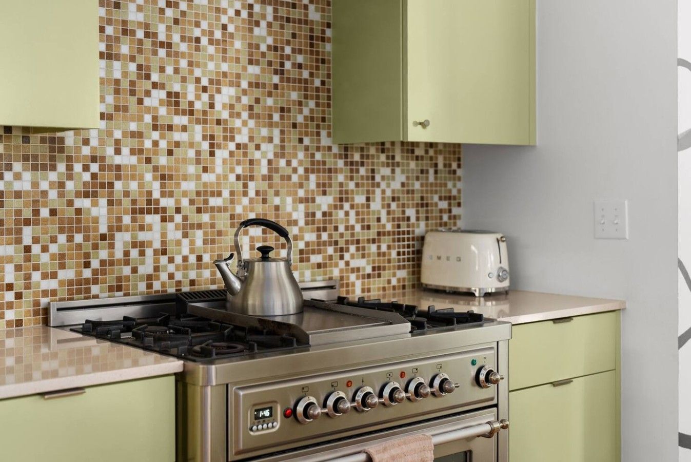 A kitchen with a gas stove, a kettle, and a toaster.