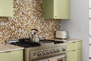 A kitchen with a gas stove, a kettle, and a toaster. - MidMod Bungalow 5BR Heated Pool (Austin)