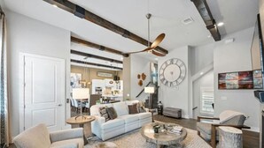 A spacious living room with a large sofa, a coffee table, and a dining area in the background. - Luxe Townhome | 4bd 5ba  Elevator | 1 mile from DT (Austin)