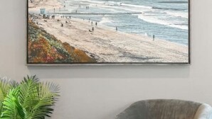 A room with a large ocean view painting, a grey armchair, a small stool with a fur throw, and a potted plant. - Luxe Townhome | 4bd 5ba  Elevator | 1 mile from DT (Austin)