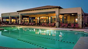 A hotel with a swimming pool, outdoor seating, and a covered area.