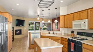 A modern kitchen with wooden cabinets, a central island, a built-in oven, a microwave, and a gas stove.