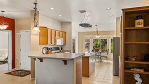 A modern kitchen with a central island, wooden cabinets, and pendant lighting.