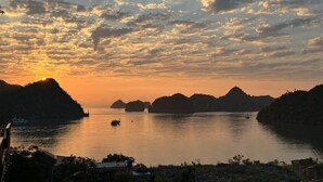 A coastal landscape with a sunset, calm water, and several boats. - Anh Quân-Viewpoint Hotel (Hai Phong)