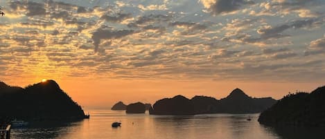 Un paisaje costero con atardecer, agua tranquila y varios barcos.