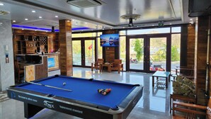 A pool table labeled "Tournament standard" in a well-lit indoor area with wooden furniture and a bar area visible through glass doors. - Anh Quân-Viewpoint Hotel (Hai Phong)