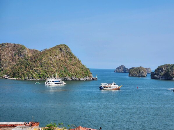 A coastal scene with boats on calm waters, surrounded by rocky islands and lush greenery. - Anh Quân-Viewpoint Hotel (Hai Phong)