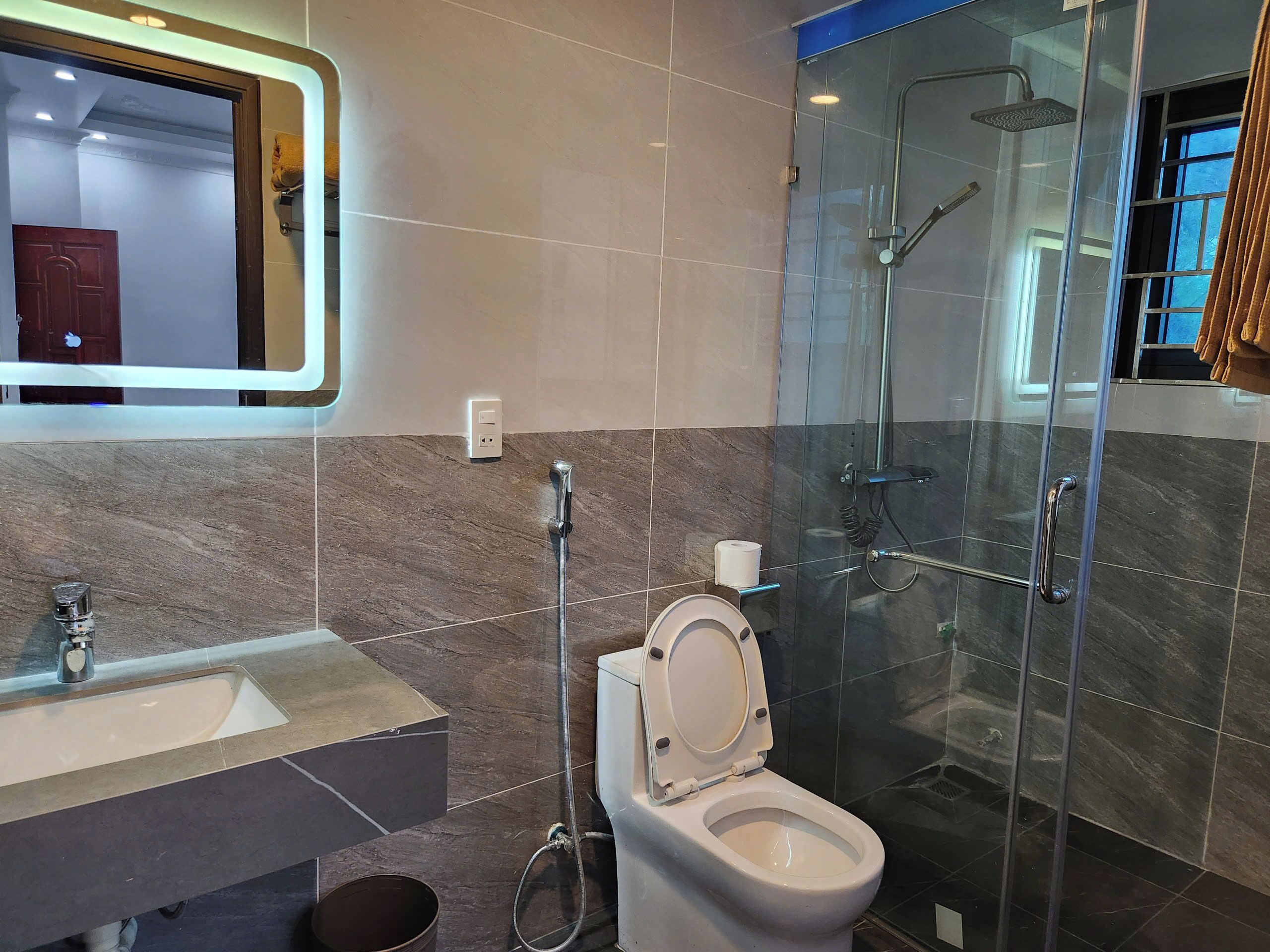 A modern bathroom with a glass-enclosed shower, a toilet, and a sink.