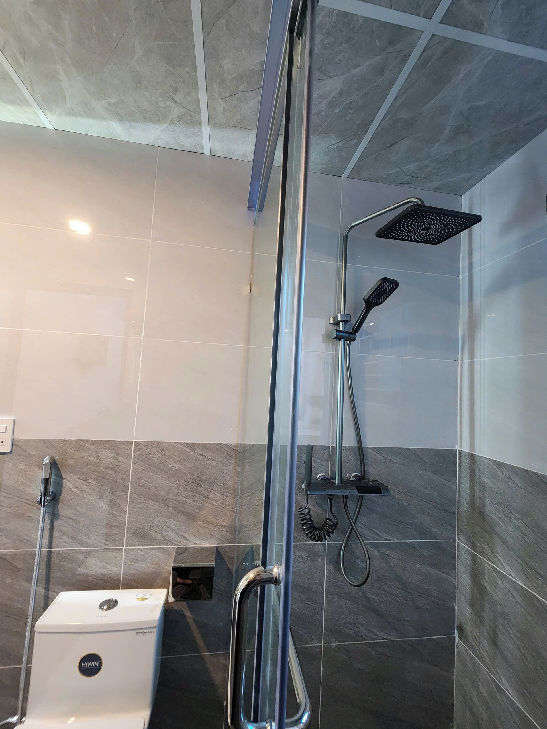 Un baño con ducha, inodoro y secador de manos.