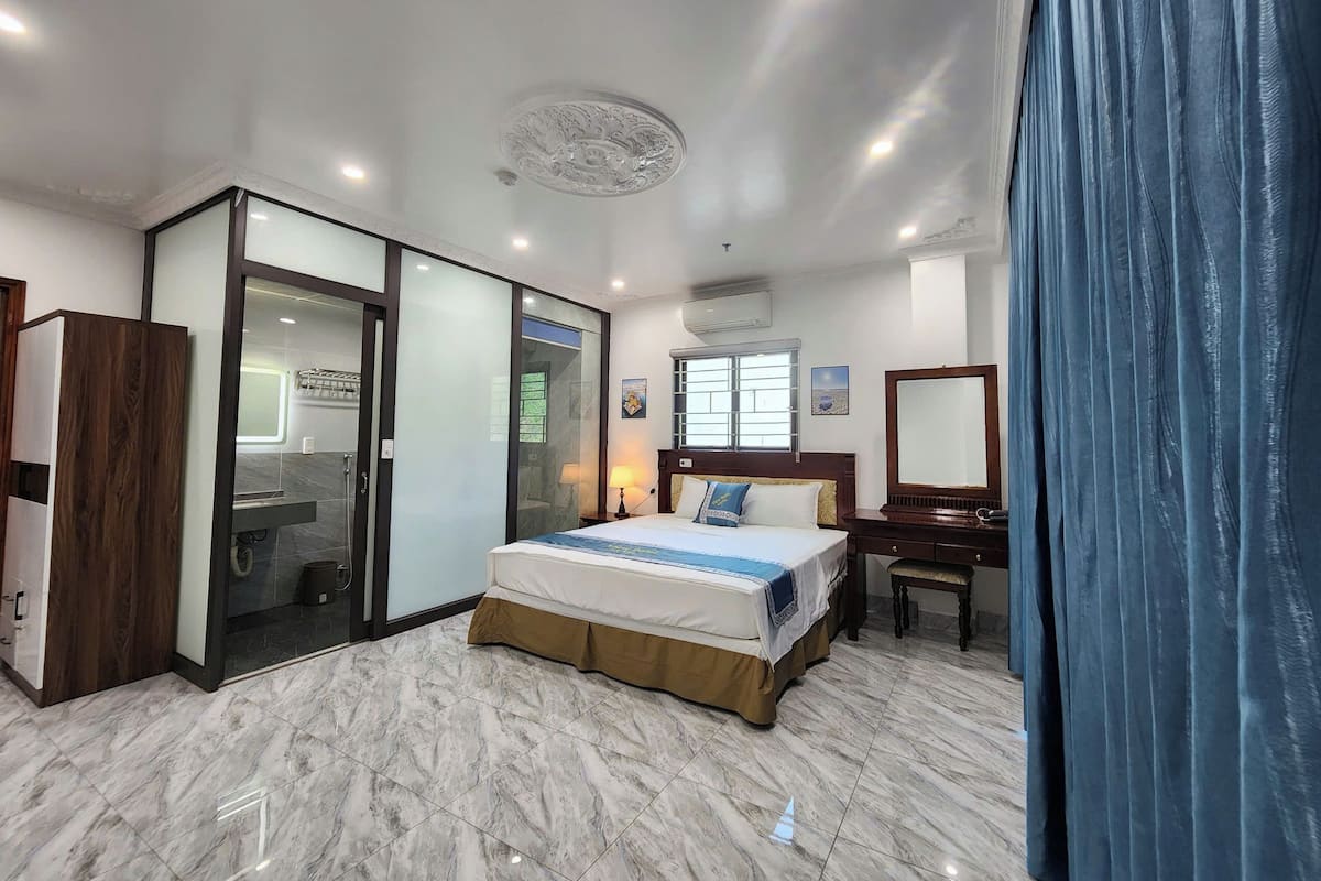 A modern hotel room with a large bed, a desk, and a walk-in closet.