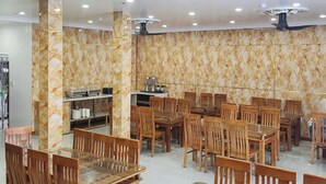 A spacious dining area with marble walls, multiple wooden tables and chairs, and ceiling lights. - Anh Quân-Viewpoint Hotel (Hai Phong)