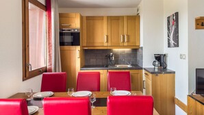 A compact kitchen with wooden cabinets, a built-in oven, and a coffee maker. - Apartment with wellness area in Les Saisies (Les Saisies)