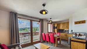 A modern apartment with a dining area, kitchen, and a balcony with a scenic view. - Apartment with wellness area in Les Saisies (Les Saisies)